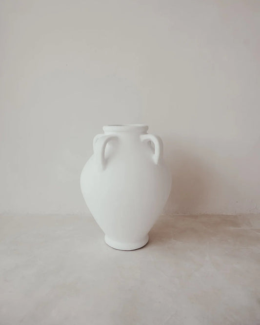 White vase with two handles on a light gray surface and background